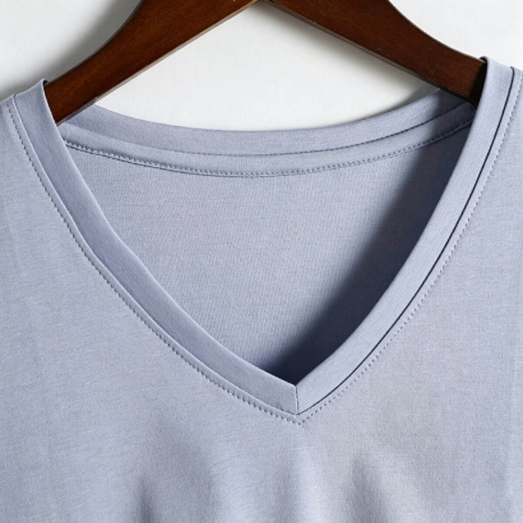 Close-up detail of the sleeve hem and fine stitching on a light blue 80S long-staple cotton T-shirt, showing durable craftsmanship.