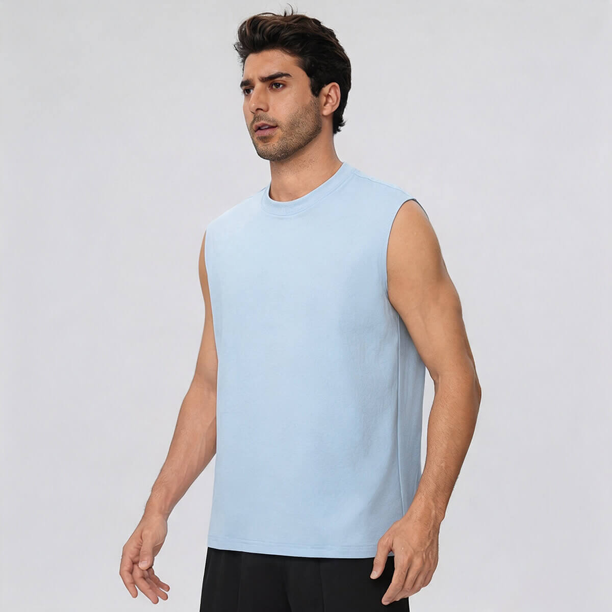 Side profile of a man in a light blue muscle tank top, showcasing the armhole cut and fit.