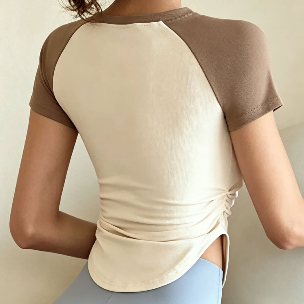 Back view of the asymmetrical curved hem activewear shirt, showing the flattering slim-fit silhouette and professional raglan shoulder construction.