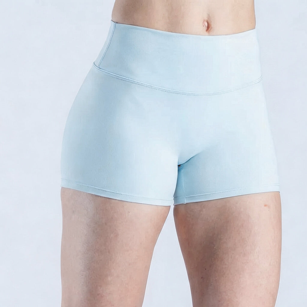 A woman wearing light sky blue athleisure fitness shorts made from high-stretch performance fabric.