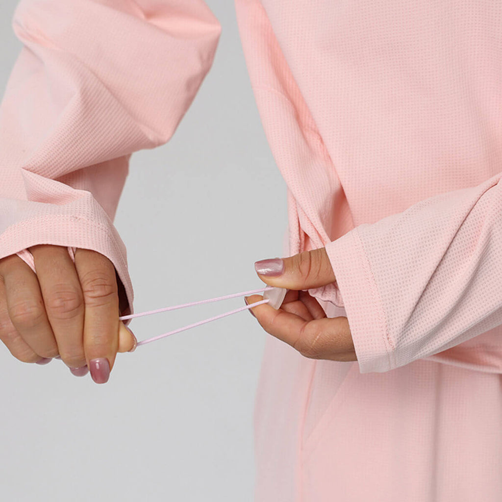 Close-up of the adjustable cinch cord and toggle at the hem of a women's cropped athletic top.