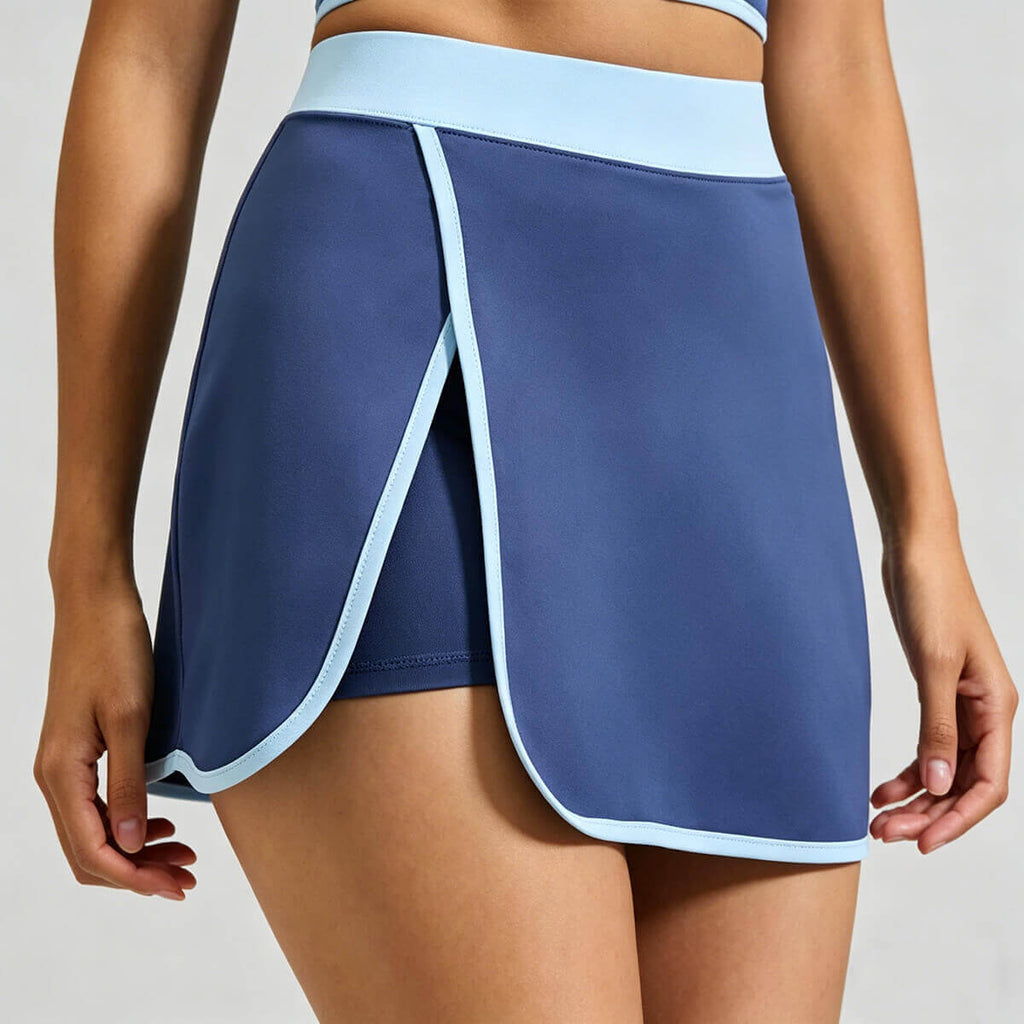 Close-up detail of the wrap front overlap design on a blue athletic skort showing the high-performance stretchy fabric