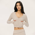 Front view of a beige slim-fit long sleeve workout jacket featuring a deep v-neckline and cropped silhouette.