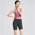 Full body front view of a model wearing black 5-inch biker shorts paired with a pink sports bra, perfect for running or summer cycling.