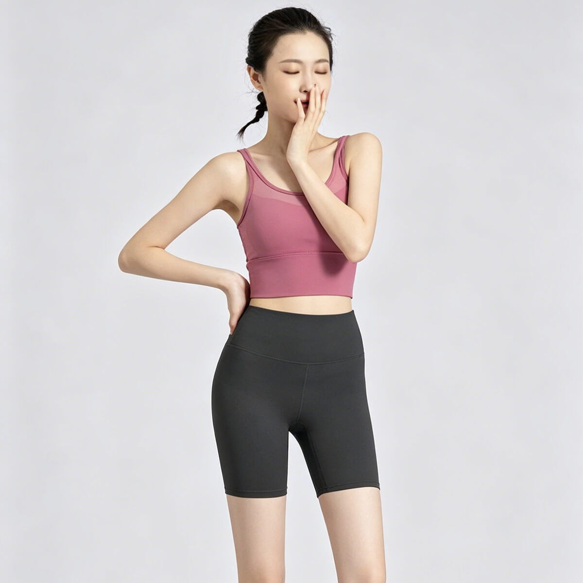Full body front view of a model wearing black 5-inch biker shorts paired with a pink sports bra, perfect for running or summer cycling.