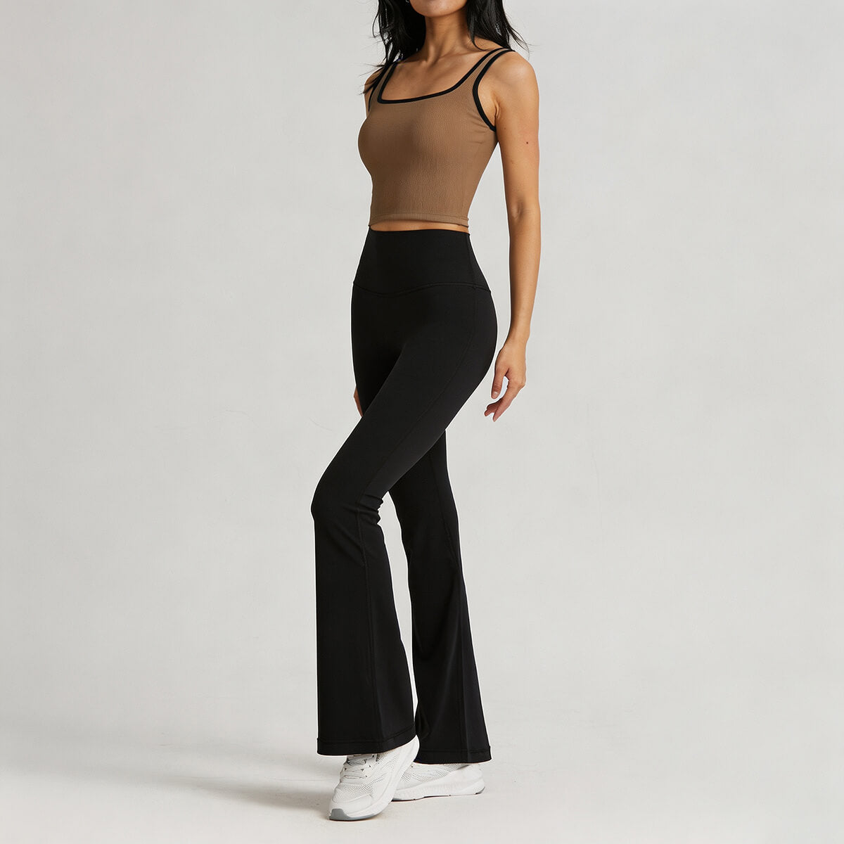 Side view of a woman styling black high-waisted flare leggings with a brown ribbed crop top for an athleisure look.