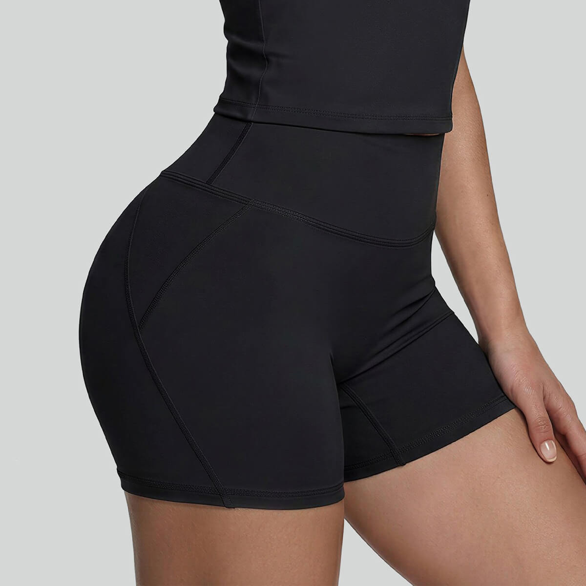 Side profile of a woman wearing black high-waisted workout shorts with body-contouring seams for a sculpted look.