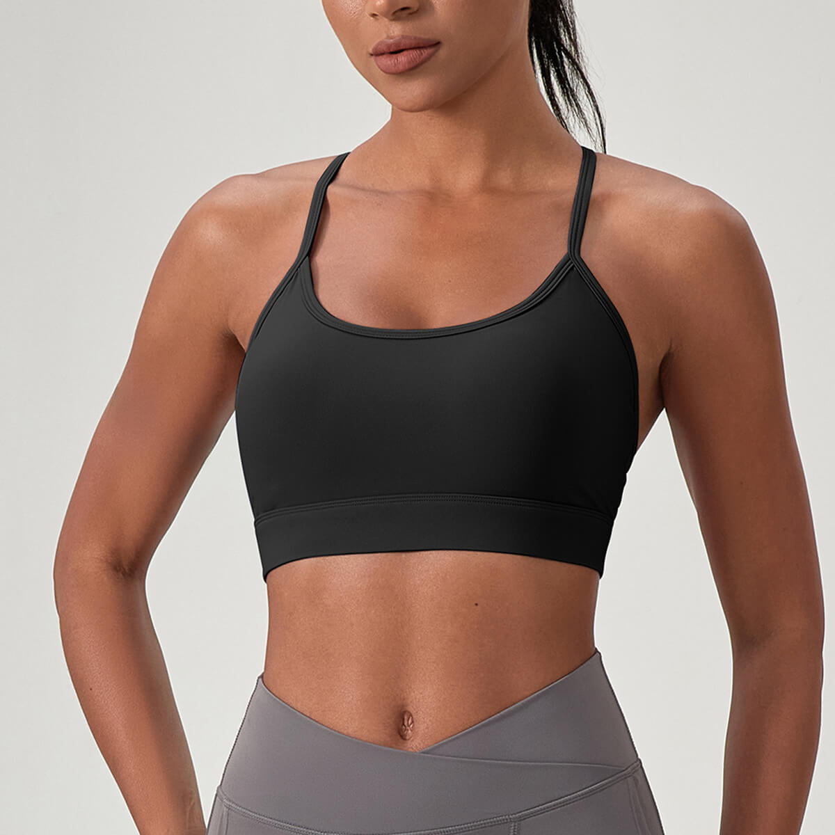 Front view of a woman wearing a black high-impact sports bra with a classic scoop neckline and wide supportive underband.