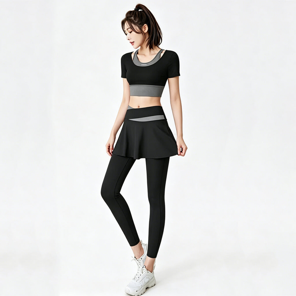 Model wearing a black skirted leggings set with a matching cropped top, featuring grey contrast waistband details for a professional gym look