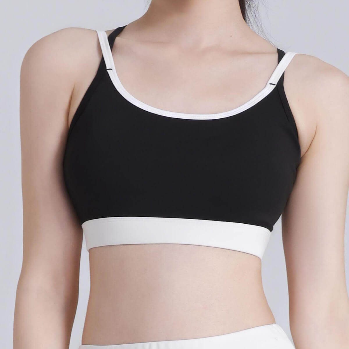Classic black sports bra with a clean white contrast trim on the neckline and band, offering a retro-inspired athletic aesthetic
