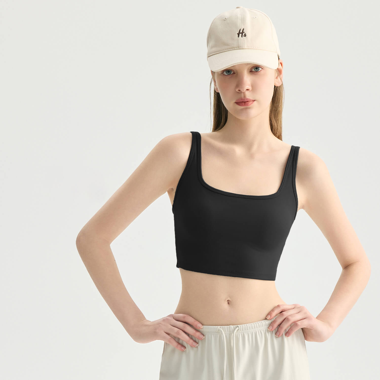 A woman wearing a classic black square neck athletic crop top, perfect for gym workouts or layering.