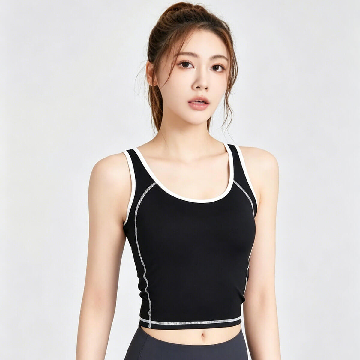 Women's black workout crop top with white contrast piping trim and visible flatlock seams for a stylish gym look