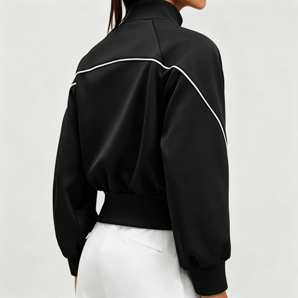 Back view of a black gym track jacket for women showing unique white curved piping detail and high-neck stand collar design.