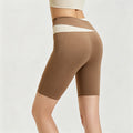 Rear side view of women's brown high-waisted biker shorts featuring a unique cream crossover waistband for tummy control.
