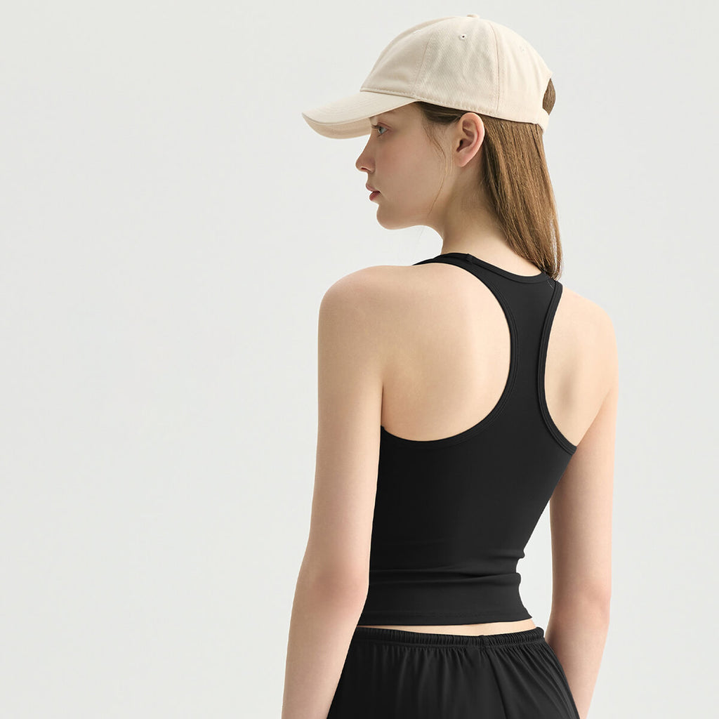 A classic black racerback fitness tank top on a woman with a beige baseball cap.