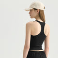 A classic black racerback fitness tank top on a woman with a beige baseball cap.