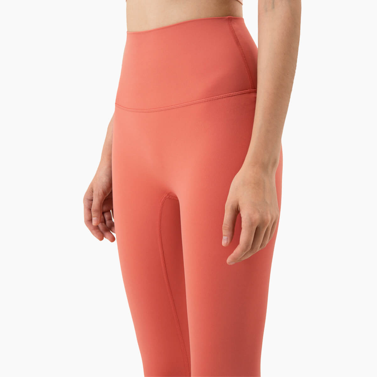 Close-up front detail of coral yoga pants showing the seamless construction to eliminate the front seam.