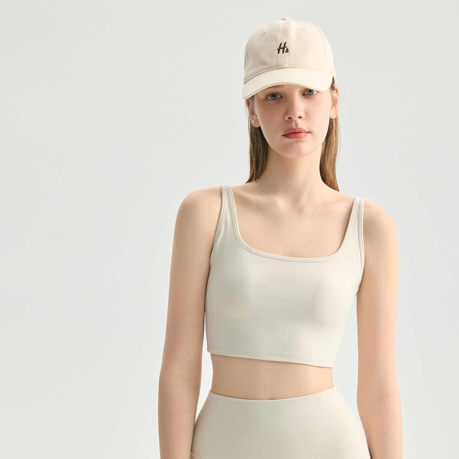 Detailed front view of a cream square neck crop tank top with a built-in bra, showing the smooth, high-quality athletic fabric.