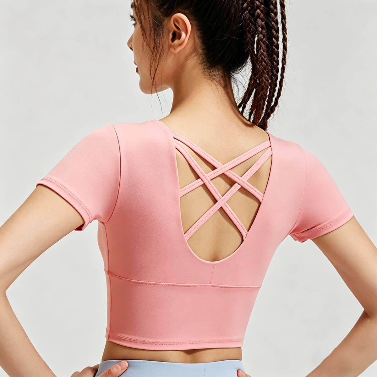 Back view of a coral peach yoga crop top showcasing a stylish multi-strap crisscross design for maximum breathability and flair.