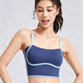 Front view of a woman wearing a dark blue yoga crop top with light blue contrast piping and thin spaghetti straps for a stylish workout