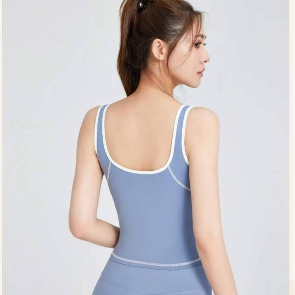 Back view of a dusty blue gym tank top with white contrast trim, showcasing the body-hugging fit and athletic silhouette