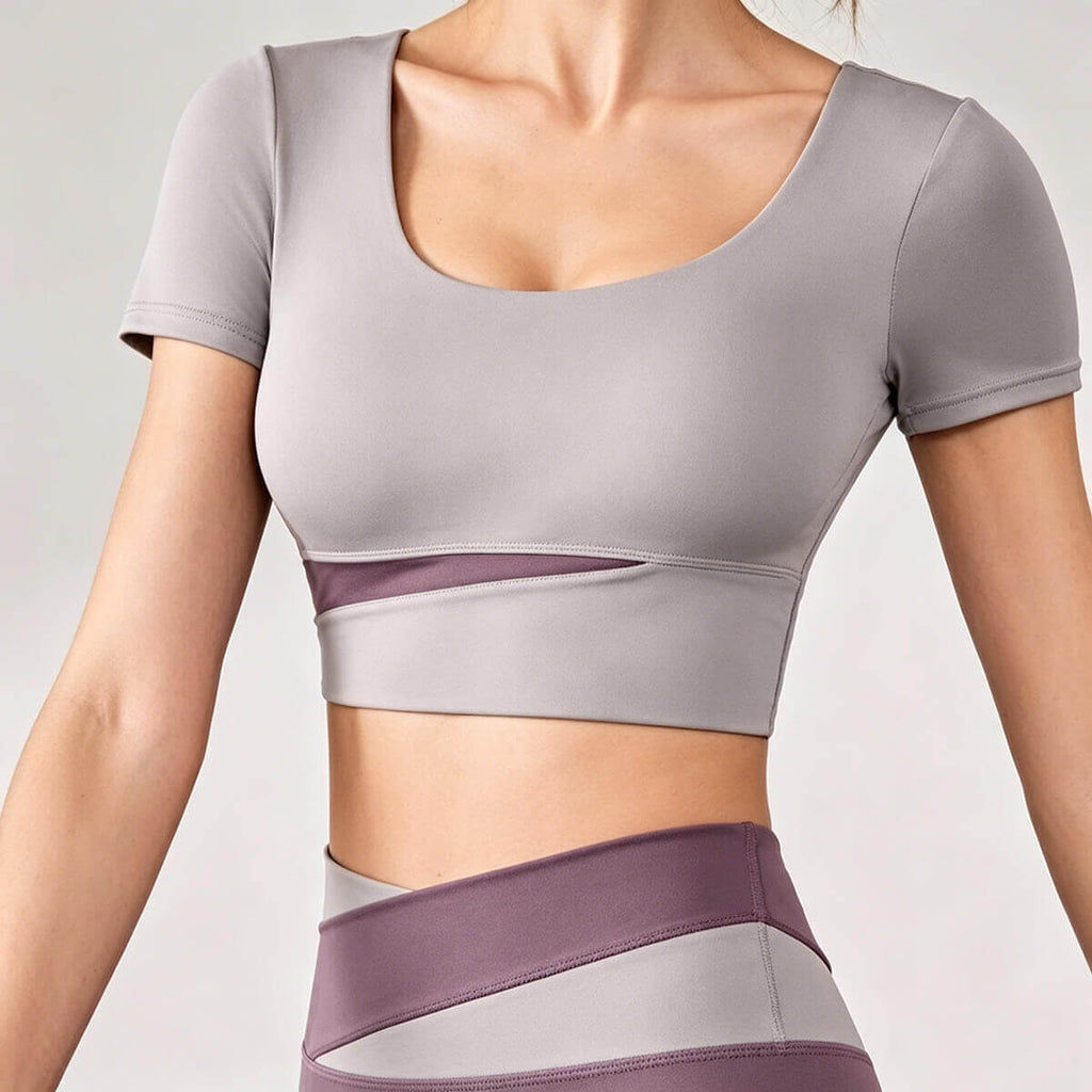 A dusty mauve or purple women's yoga crop top featuring a fashionable mesh cutout and supportive scoop neckline for active lifestyles