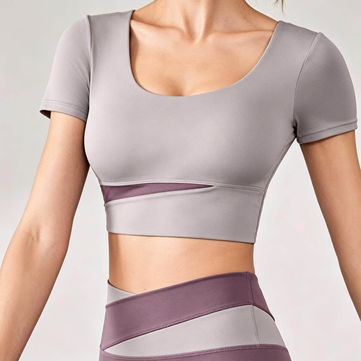 A dusty mauve or purple women's yoga crop top featuring a fashionable mesh cutout and supportive scoop neckline for active lifestyles