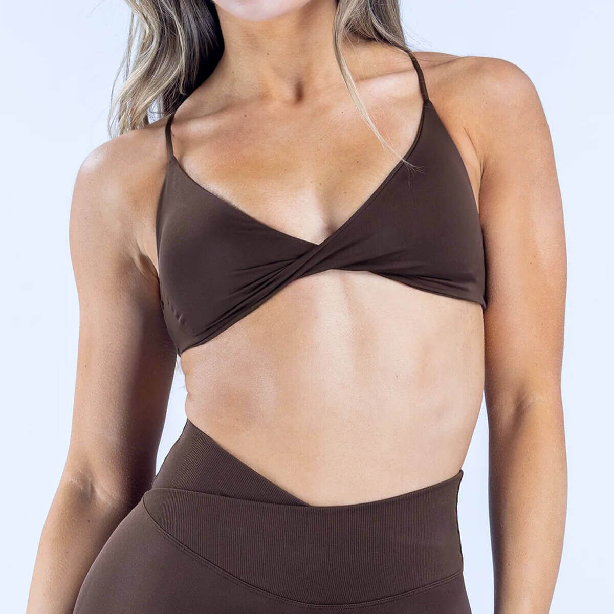 An espresso brown performance sports bra featuring a central twist and delicate spaghetti straps.