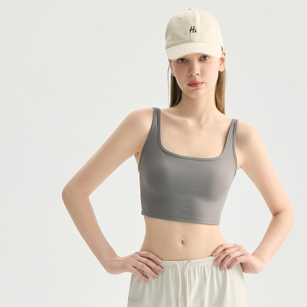 Front view of a woman wearing a charcoal gray square neck workout tank top posing with hands on hips.