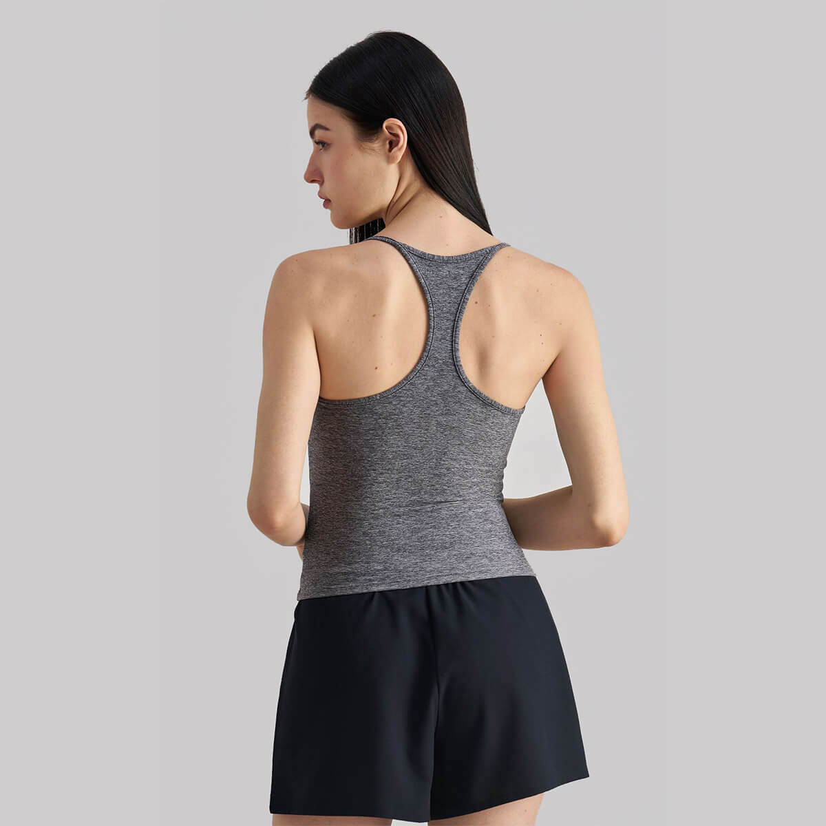 Back view of a woman wearing a heather gray athletic tank top showing the racerback design.