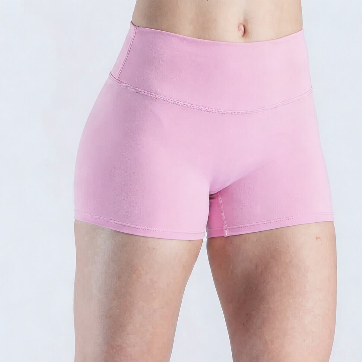 Front view of a model in blush pink high-rise booty shorts, ideal for gym and fitness training.