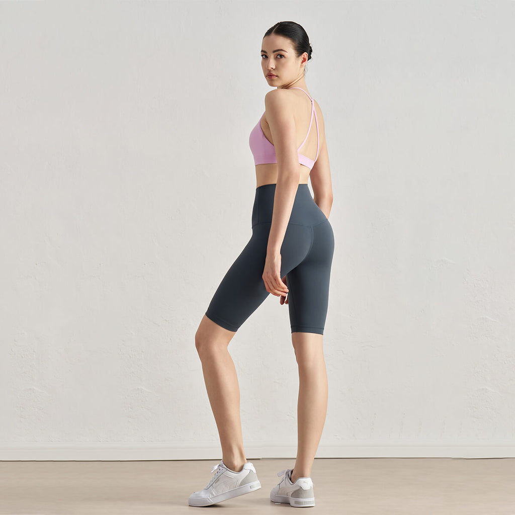 Side profile of a woman in grey high-waisted biker shorts showing the elongating silhouette.