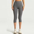 Front view of a woman wearing charcoal grey high-waisted capri leggings with tummy control waistband for fitness