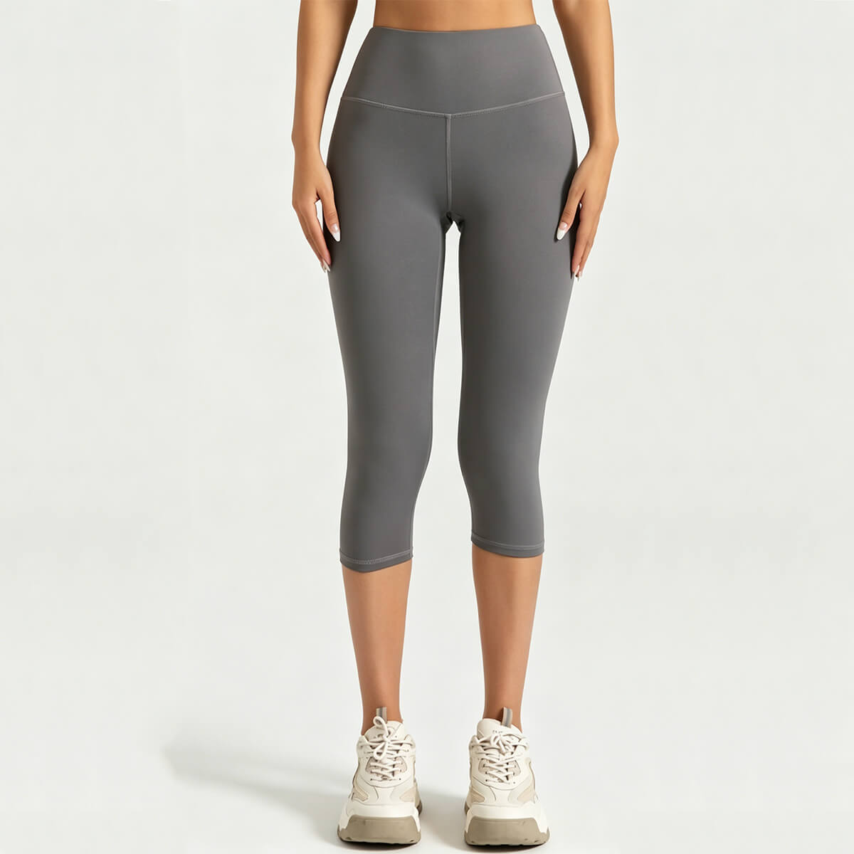 Front view of a woman wearing charcoal grey high-waisted capri leggings with tummy control waistband for fitness