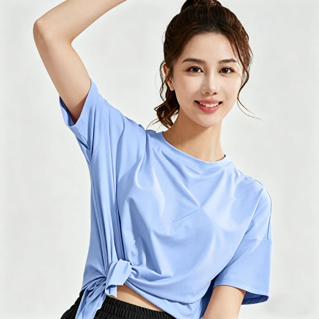 Model wearing a light blue oversized athletic top tied in a front knot, showing its versatility for both workout and casual athleisure wear.