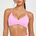 Close-up front view of a light pink V-neck athletic bralette with thin straps, providing gentle support and a feminine aesthetic