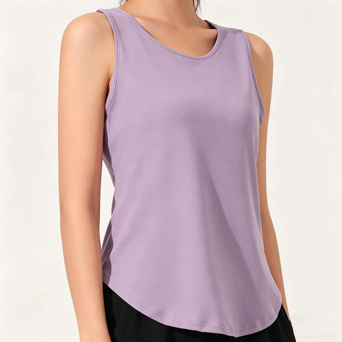 Angled view of a lilac sleeveless workout shirt for women showcasing the stylish curved tulip hem