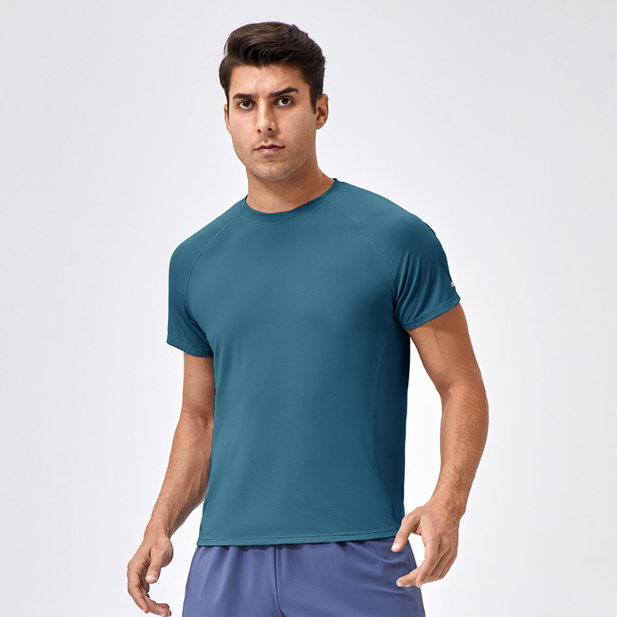 A man in a deep teal quick-dry fitness T-shirt, highlighting the ergonomic seam design.