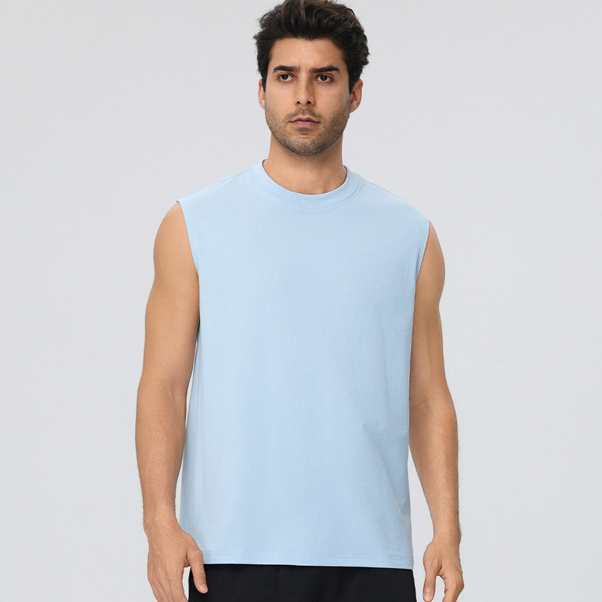 Front view of a man wearing a sky blue performance muscle tee for fitness training.