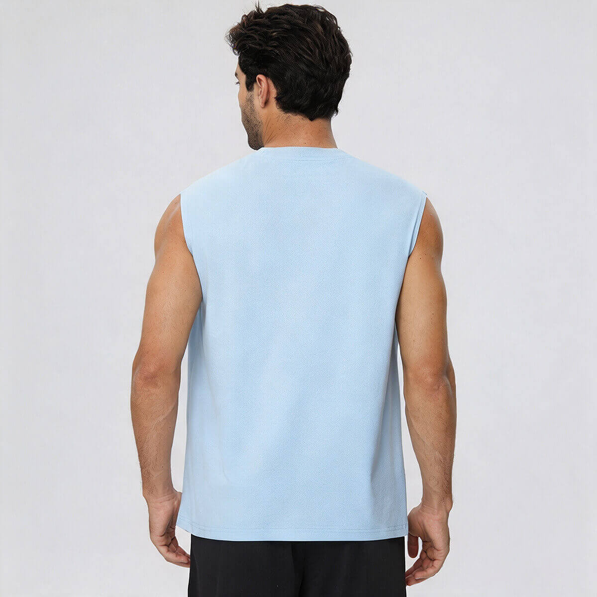 Rear view of a man wearing a light blue sleeveless performance tee, showing the athletic fit.