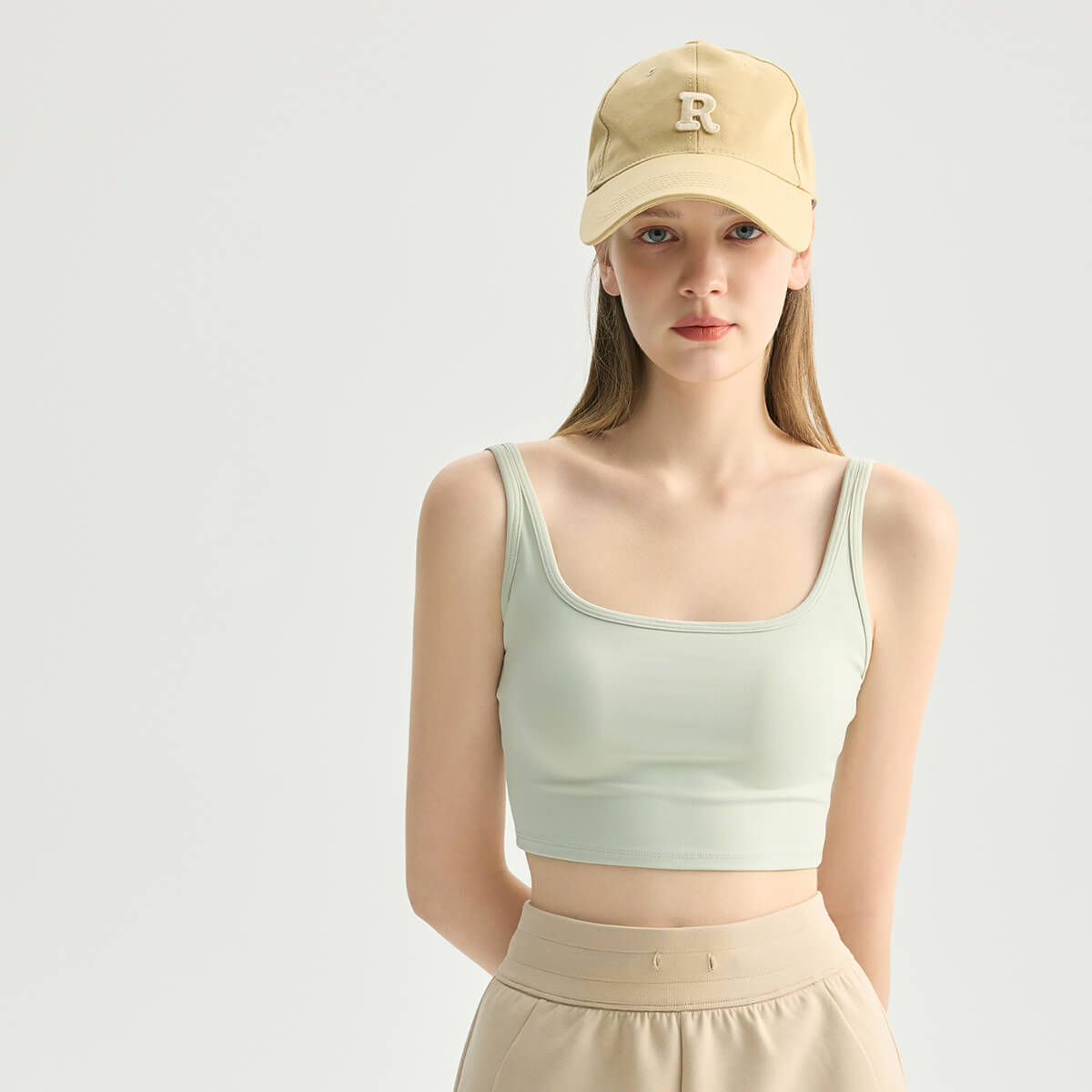 A woman wearing a mint green slim-fit gym crop tank top, ideal for yoga and Pilates.