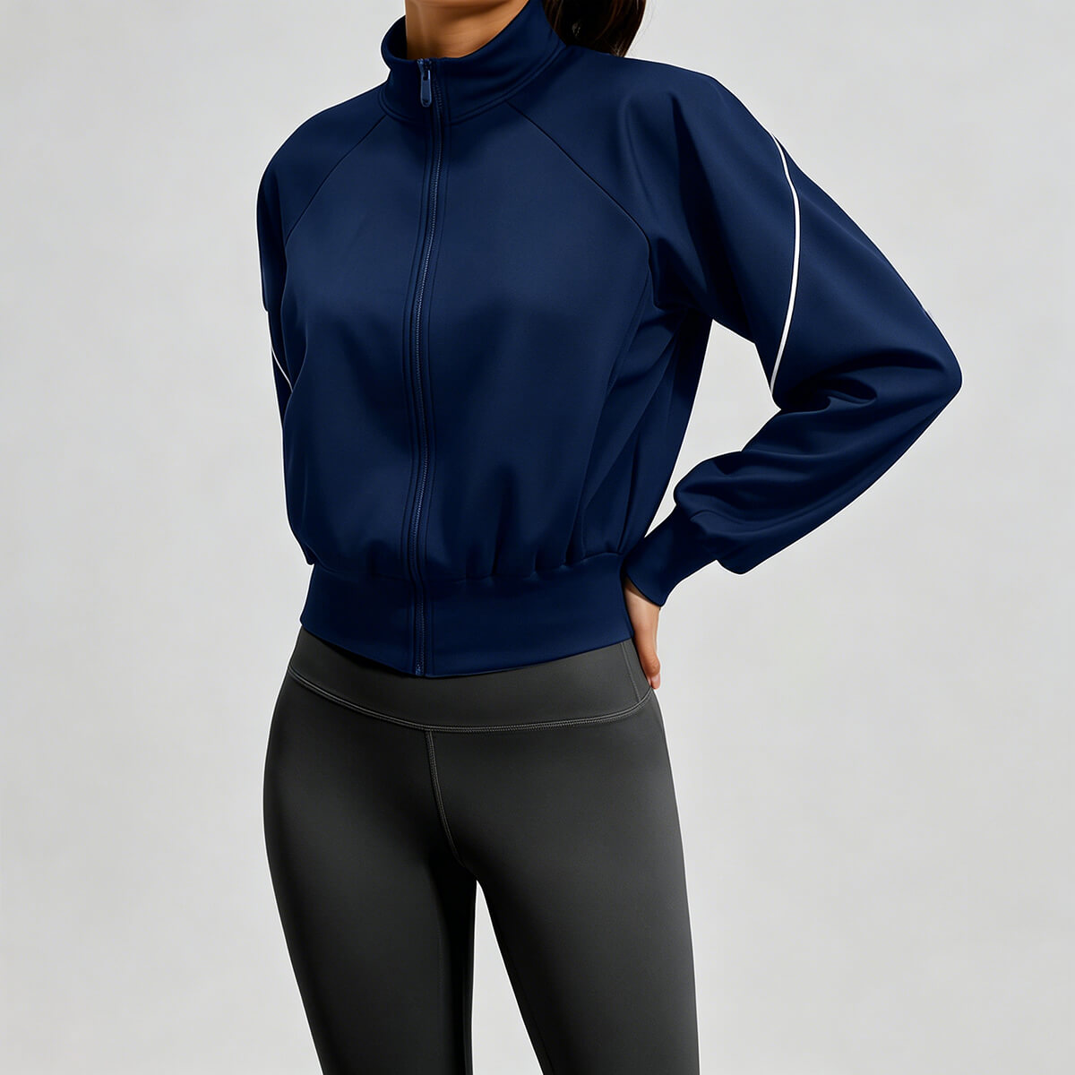 Women's navy blue athletic bomber jacket with white piping on sleeves, paired with dark leggings for a stylish fitness look.