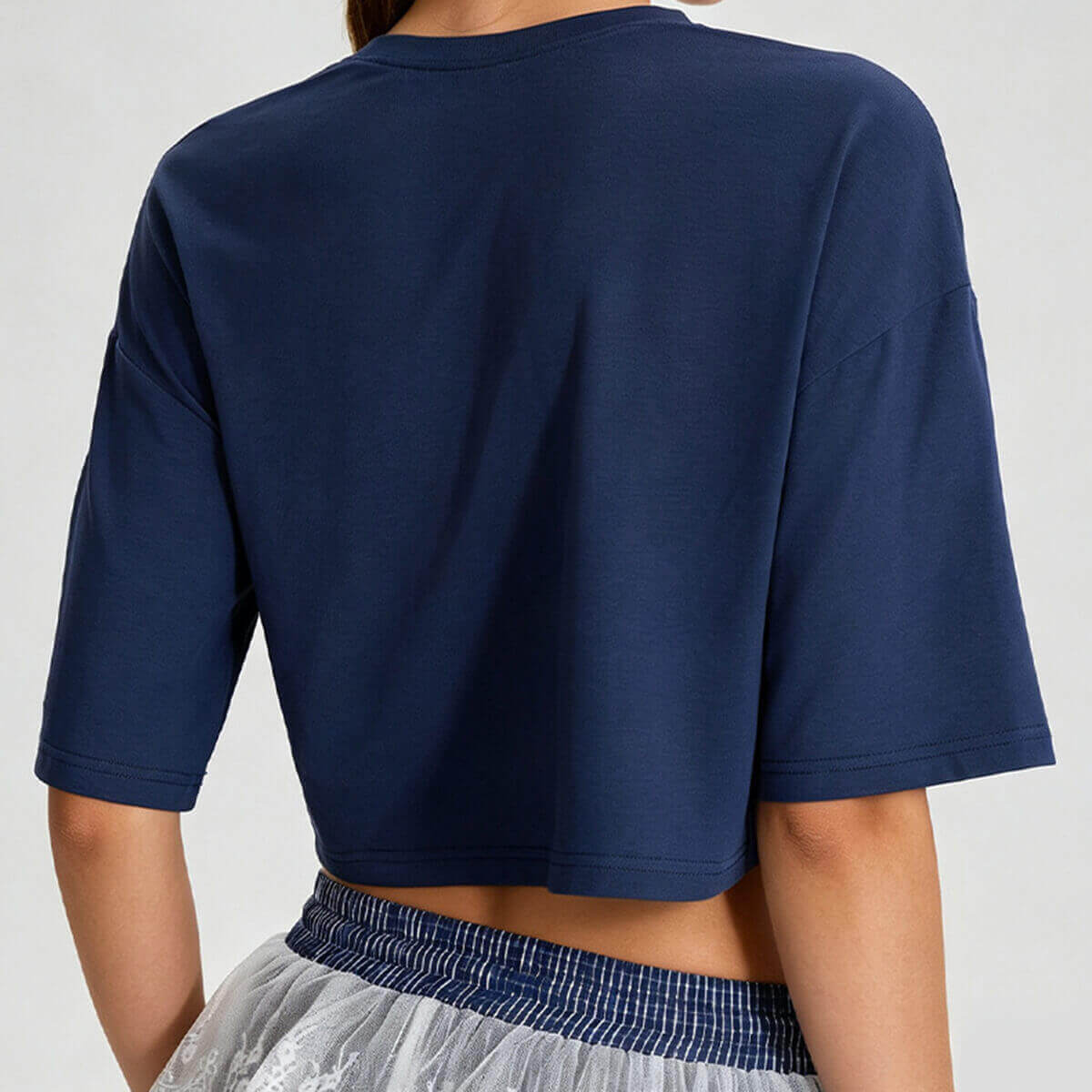 Rear view of a navy blue cropped workout shirt showing the loose boxy cut and drop shoulder seams.