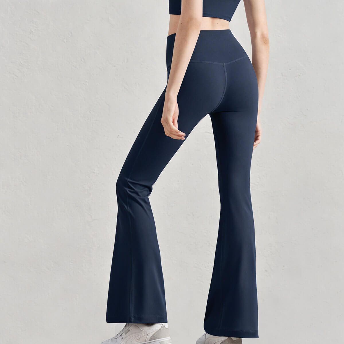 Back view of navy blue high-rise flare workout pants featuring a supportive wide waistband for tummy control.
