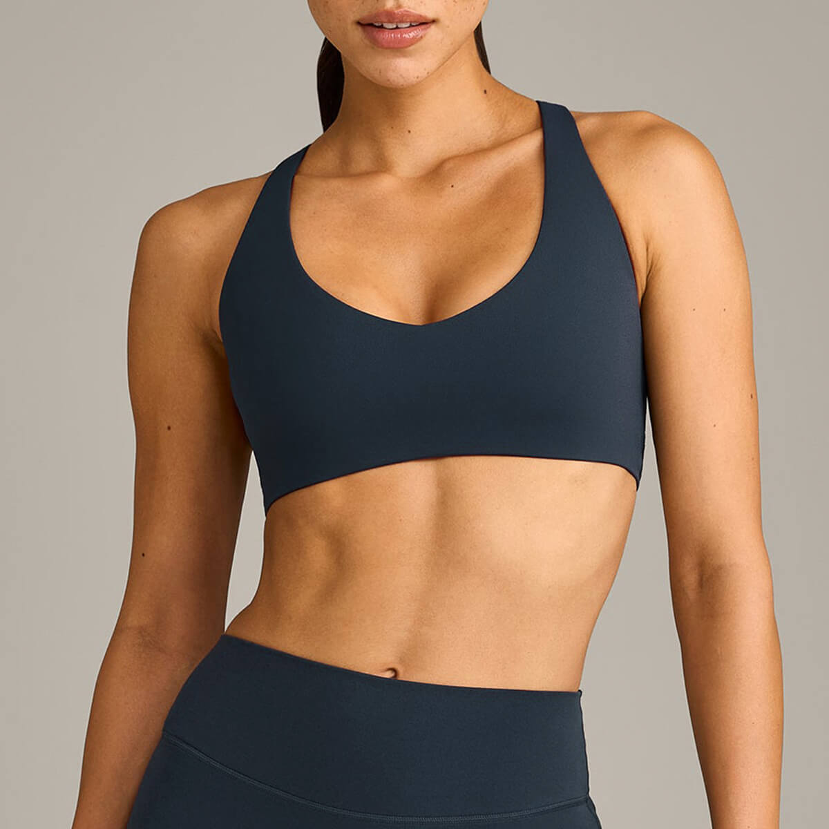 A woman modeling a navy blue athletic sports bra with a comfortable stretch fit for athletic training.