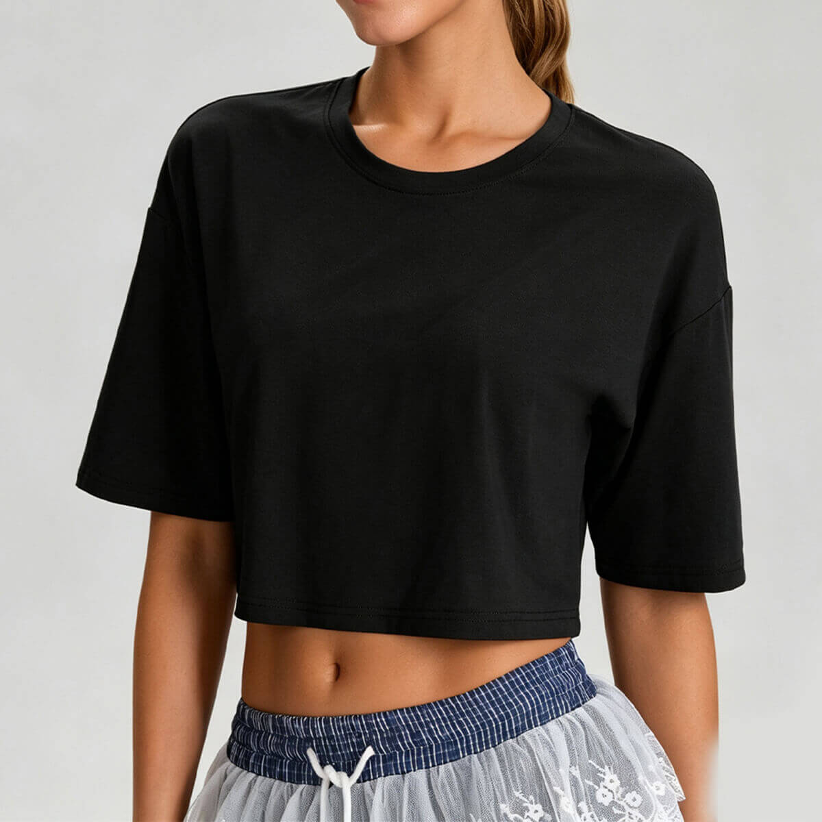 A woman wearing a black oversized gym crop top with a modern boxy silhouette, perfect for pairing with high-waisted leggings.