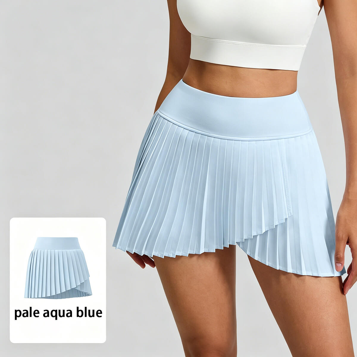 Pale aqua blue pleated athletic skort with asymmetrical hem and high waistband, premium activewear for studio boutiques.