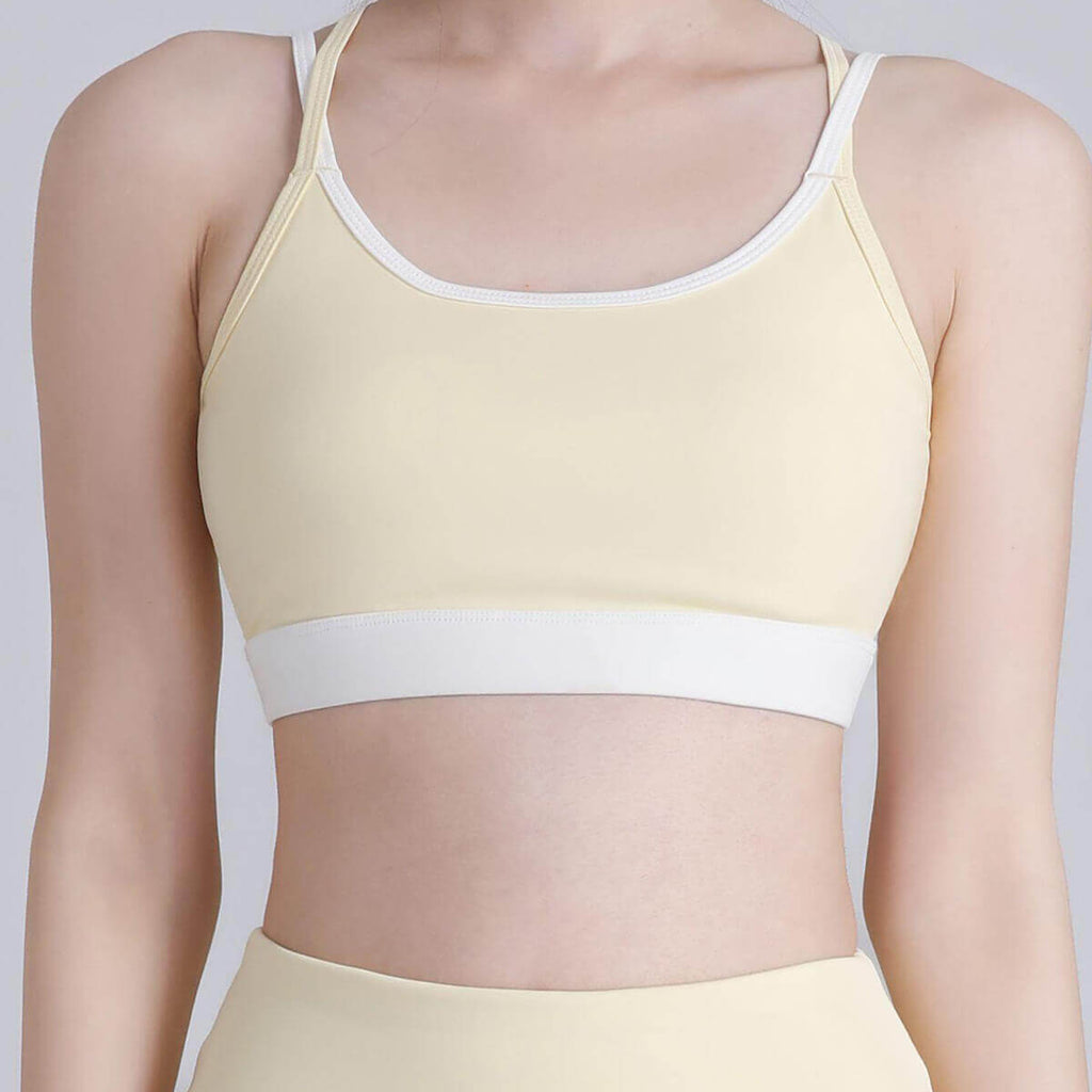 Front view of a pale yellow activewear bra top with white borders, ideal for low to medium impact exercises like yoga and pilates