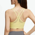 Back view of a pastel yellow racerback yoga bra with mesh inserts and supportive wide under-bust band for medium impact workouts