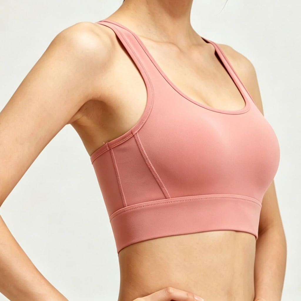 Side profile of a seamless peach-colored workout bra showing the supportive under-bust band and smooth performance fabric